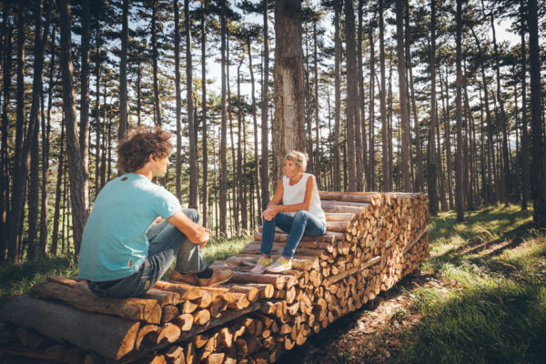 Zwei Personen auf Holz sitzend im Wald