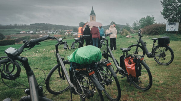 Gruppe mit Schirmen hinter Fahrrädern