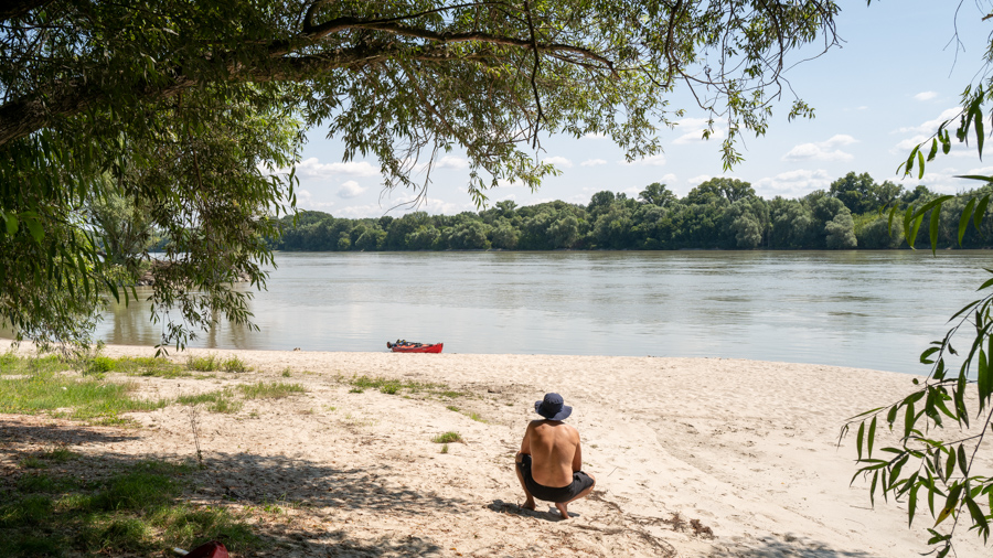 Mann macht Pause im Schatten am Ufer der Donau.