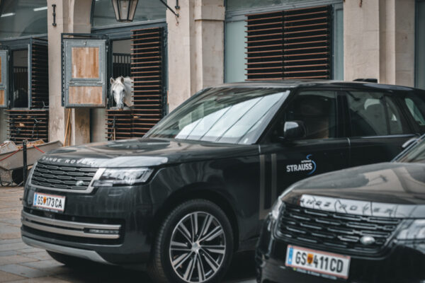 ein Pferd schaut auf einen geparkten Range Rover in der Spanischen Hofreitschule